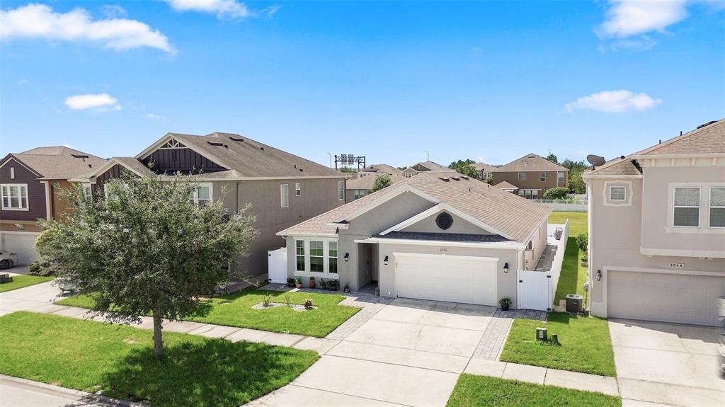 A suburban street view shows a gray single-story house with a white garage and lawn — 2050 BEACON LANDING CIRCLE, ORLANDO, FL