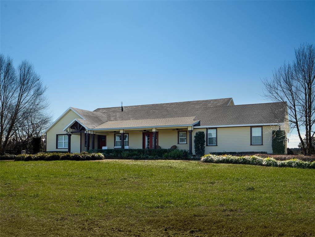 A yellow, single-story house with a covered front porch sits behind a large green lawn — 11130 W HIGHWAY 326, OCALA, FL