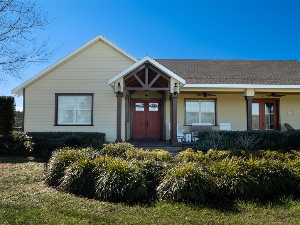 A single-story house with light yellow siding, a covered front porch, and a red door — 11130 W HIGHWAY 326, OCALA, FL