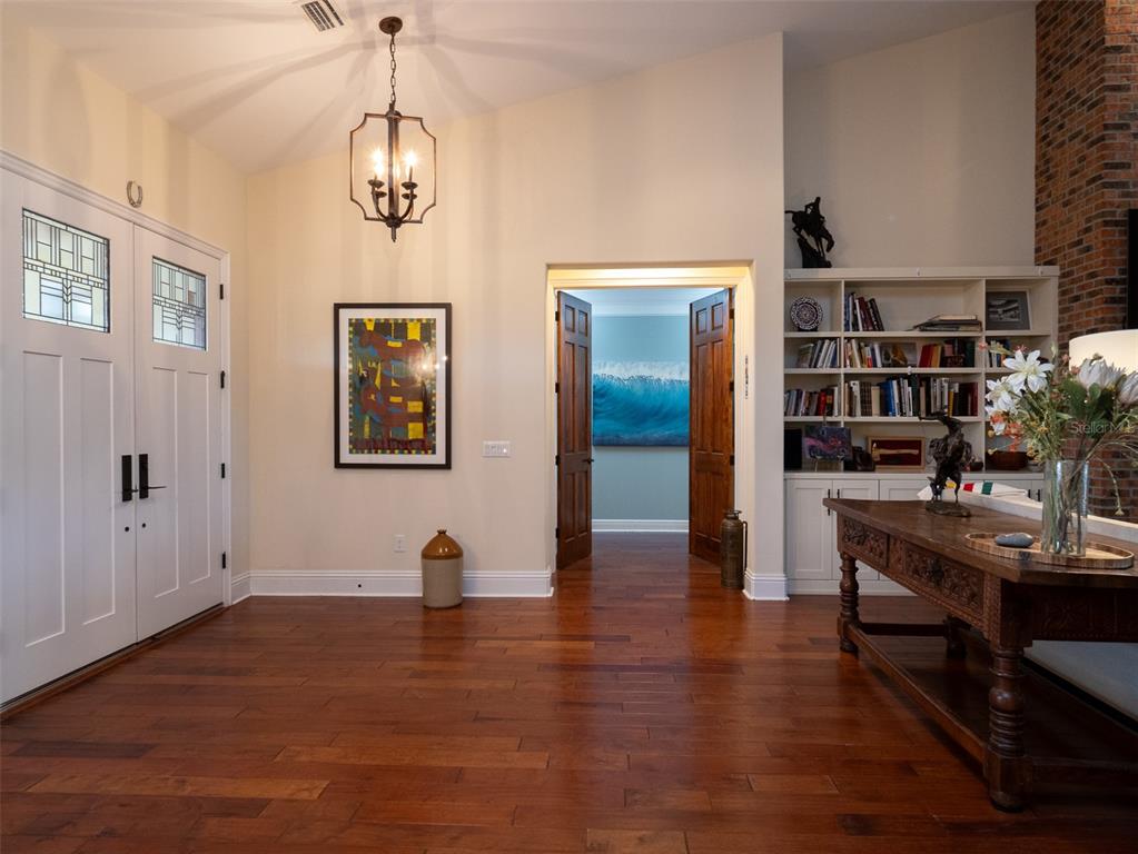 An entryway with hardwood floors, a chandelier, a wooden console table, and a built-in bookshelf — 11130 W HIGHWAY 326, OCALA, FL