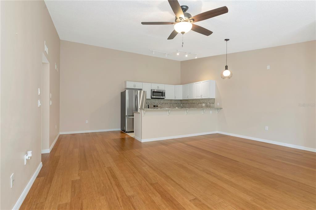 An open-concept kitchen features white cabinetry, stainless steel appliances, and wood flooring — 3367 CRYSTAL COURT E UNIT E, PALM HARBOR, FL