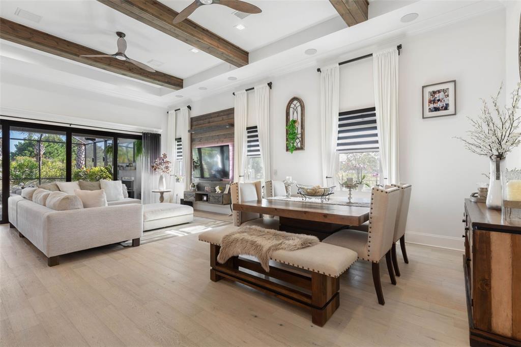 A living and dining room with wood ceiling beams, light wood floors, and a sectional sofa — 2 DEL PALMA DRIVE, PALM COAST, FL