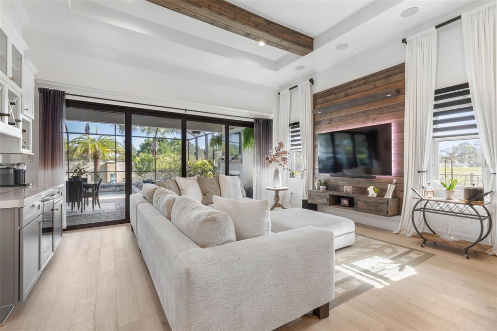 A living room features a wood-paneled accent wall, a sectional sofa, and sliding glass doors — 2 DEL PALMA DRIVE, PALM COAST, FL