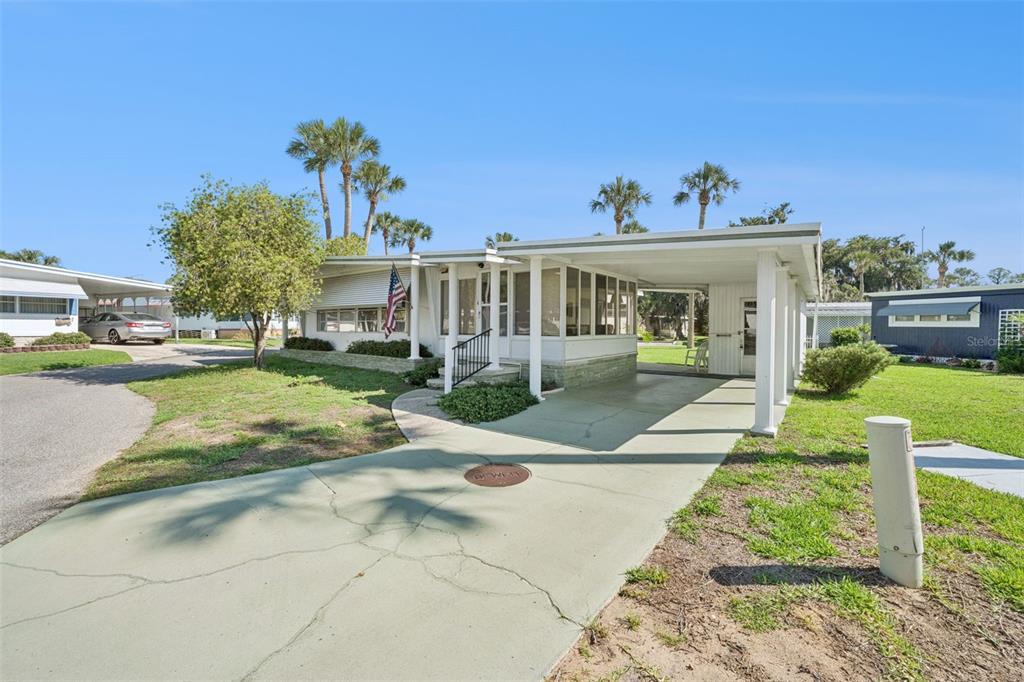 A single-story mobile home features a screened-in porch, a carport, and a concrete driveway — 43 SABAL PALM CIRCLE, EUSTIS, FL