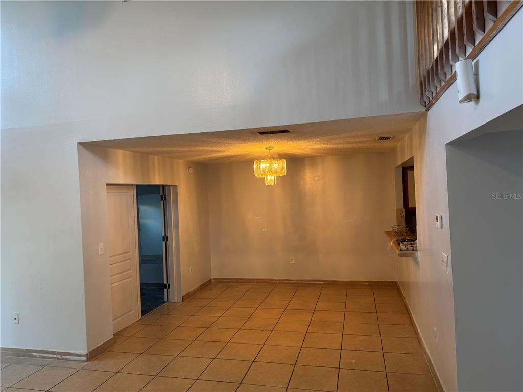 A dining area features tan tile flooring, a tiered chandelier, and an open pass-through window — 1212 INDIAN BLUFF DRIVE, APOPKA, FL