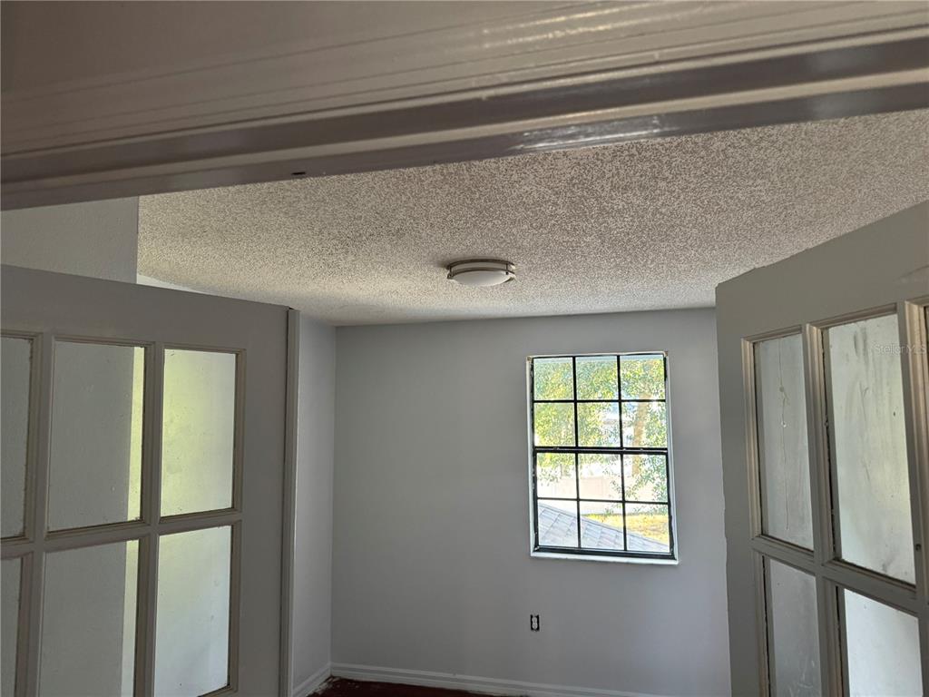 A room with a textured ceiling, a central light fixture, and a window with panes — 1212 INDIAN BLUFF DRIVE, APOPKA, FL