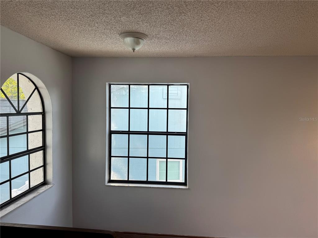 An interior view shows a room with a popcorn ceiling, a square window, and an arched window — 1212 INDIAN BLUFF DRIVE, APOPKA, FL