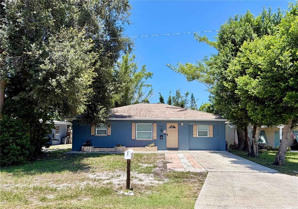 A blue single-story house features a tan front door, light-colored shutters, and a concrete driveway — 6353 FLORIDA AVENUE, NEW PORT RICHEY, FL