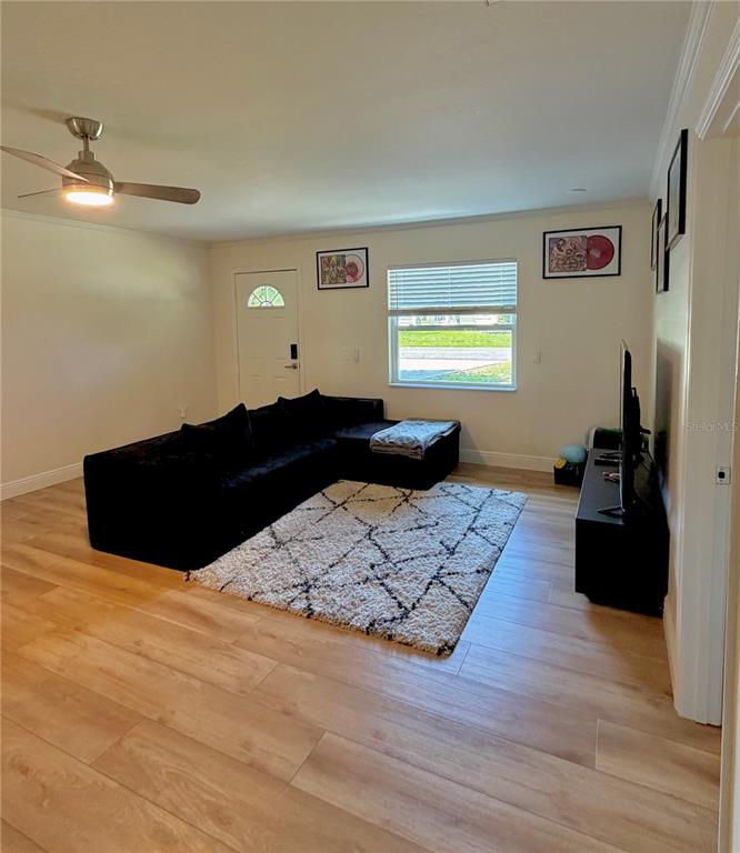A living room features light wood flooring, a black sectional sofa, and a white rug — 6353 FLORIDA AVENUE, NEW PORT RICHEY, FL