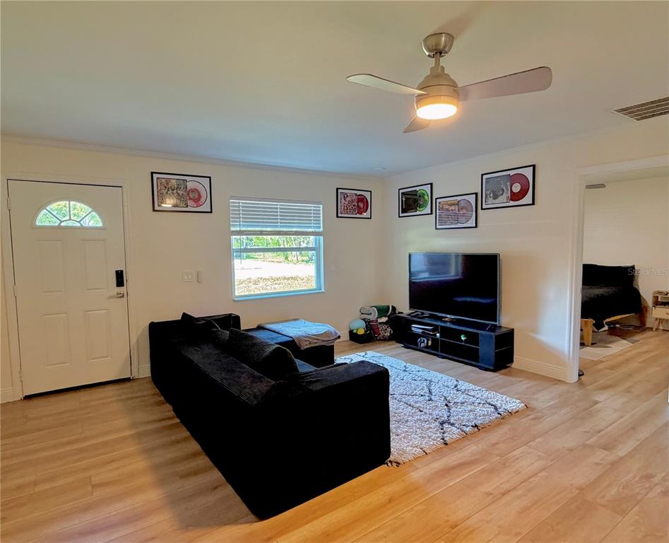 A living room features light wood flooring, a black sectional sofa, and framed vinyl records — 6353 FLORIDA AVENUE, NEW PORT RICHEY, FL