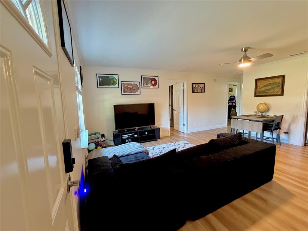 A living room features a black sectional sofa, a television on a stand, and wood-look flooring — 6353 FLORIDA AVENUE, NEW PORT RICHEY, FL