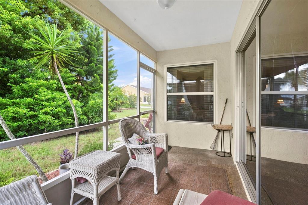 A screened-in patio with wicker furniture, tile flooring, and a view of the backyard — 7637 BALHARBOUR DRIVE, NEW PORT RICHEY, FL