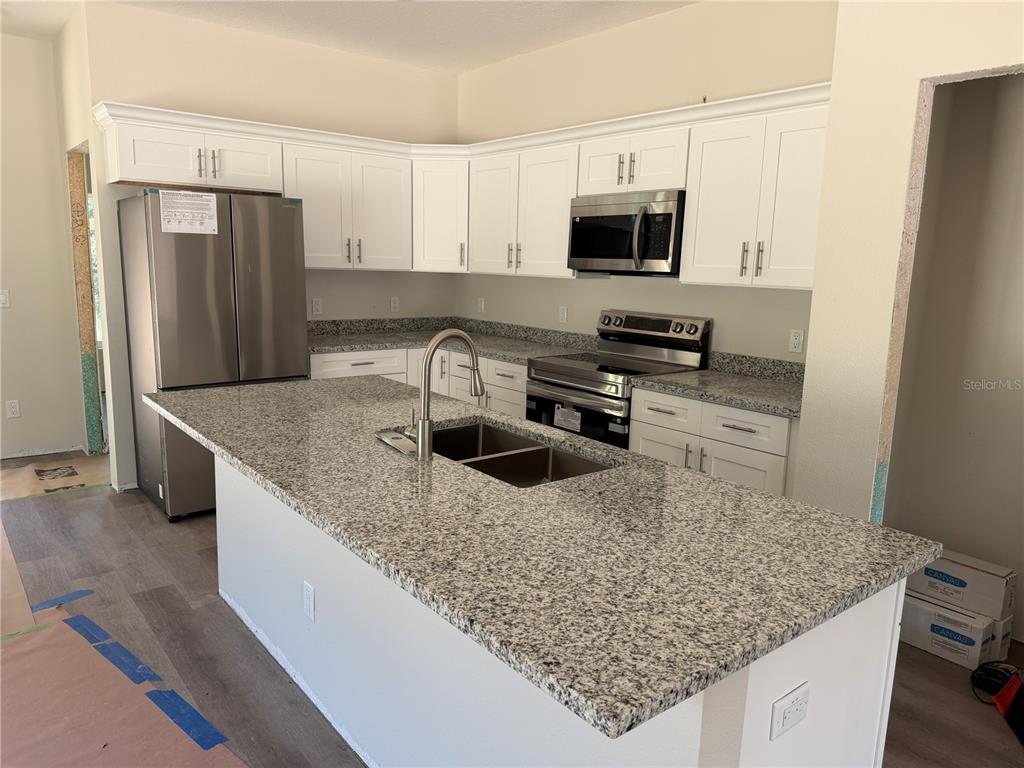 An unfinished room features gray walls, a white entry door, a window, and stacked flooring materials — 34281 MANUEL STREET, WEBSTER, FL