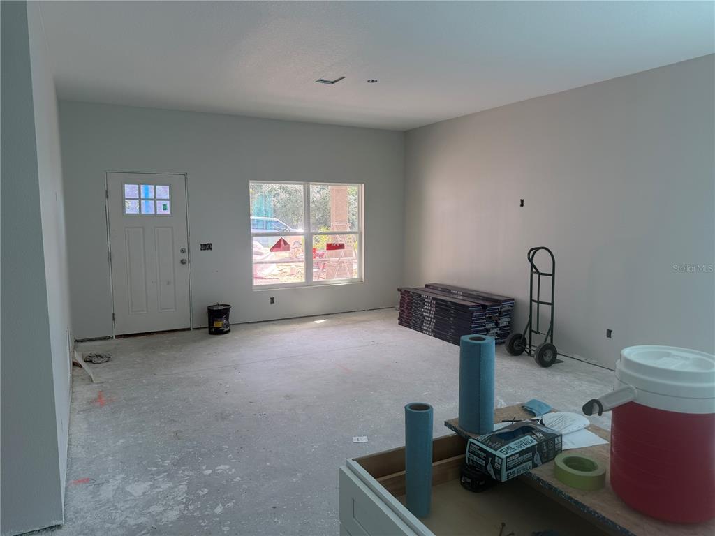 An unfinished room features gray walls, a white entry door, a window, and stacked flooring materials — 34281 MANUEL STREET, WEBSTER, FL