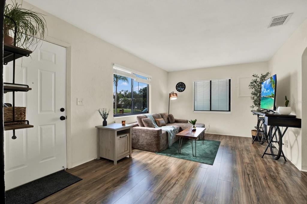 A living room features wood-look flooring, a sectional sofa, a coffee table, and two windows — 1907 53RD STREET S, GULFPORT, FL