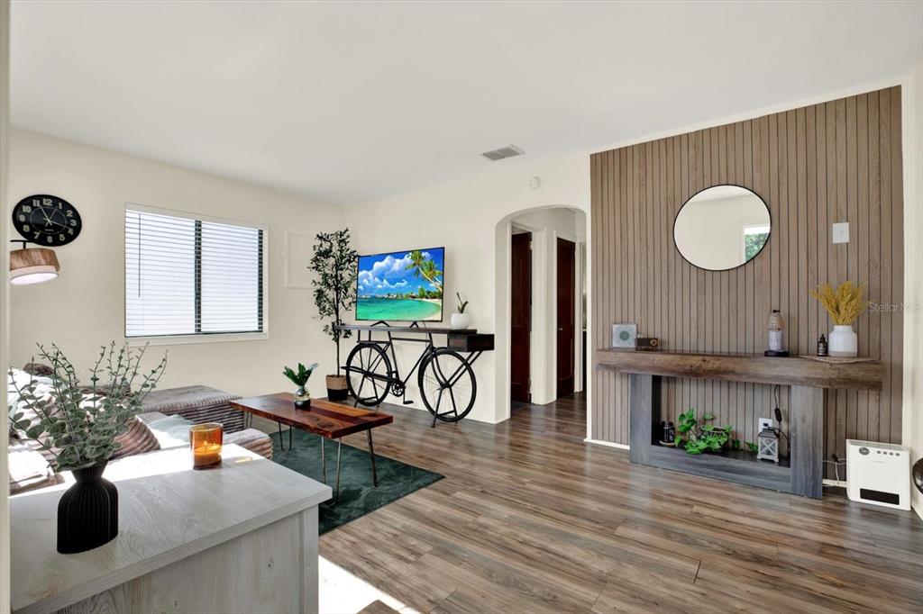 A living room features wood-look flooring, a slatted wood accent wall, and a bicycle-themed console table — 1907 53RD STREET S, GULFPORT, FL