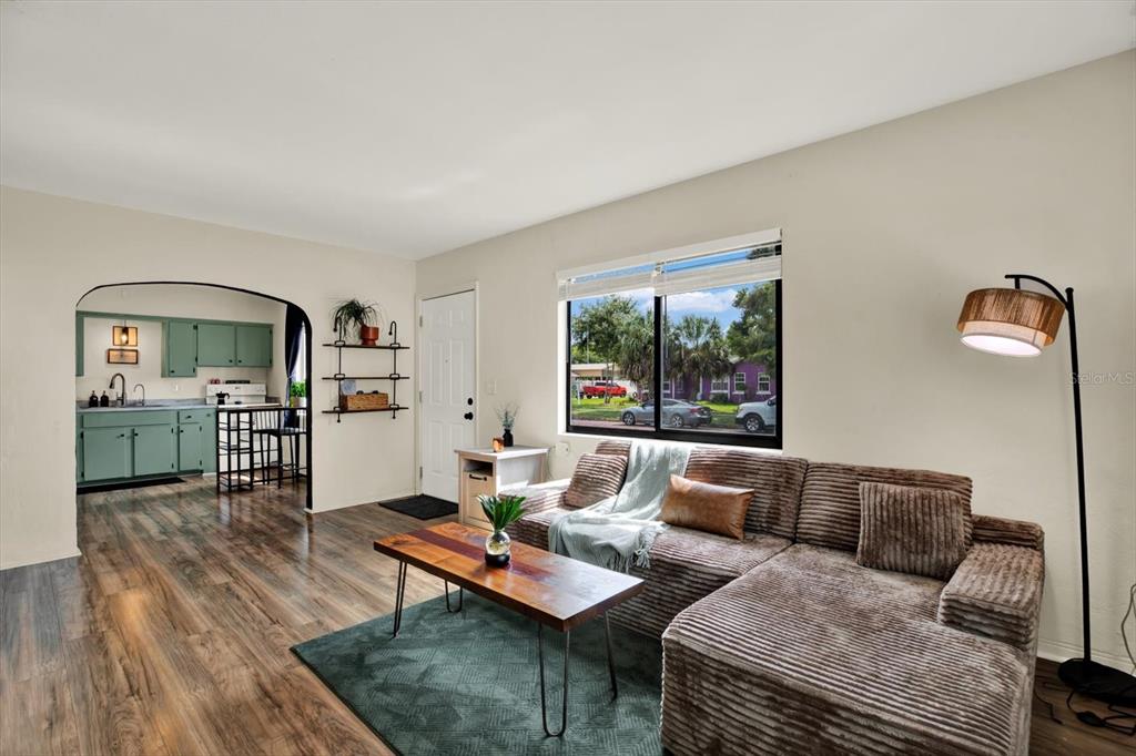 A living room with a brown sectional sofa, wood coffee table, and an arched kitchen doorway — 1907 53RD STREET S, GULFPORT, FL