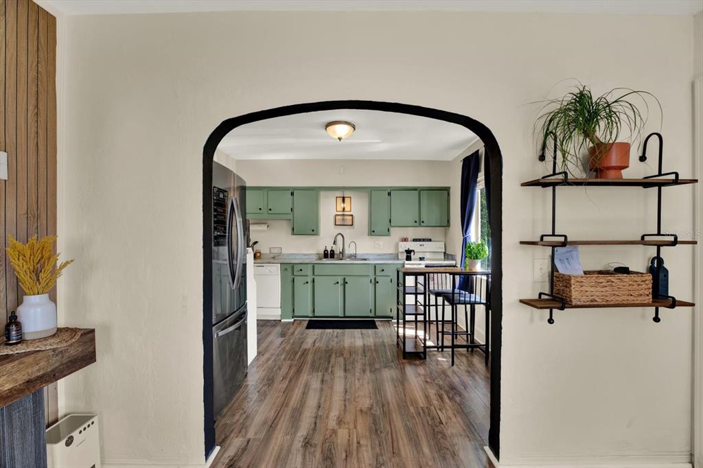 A view through an arched doorway into a kitchen with green cabinets and wood flooring — 1907 53RD STREET S, GULFPORT, FL
