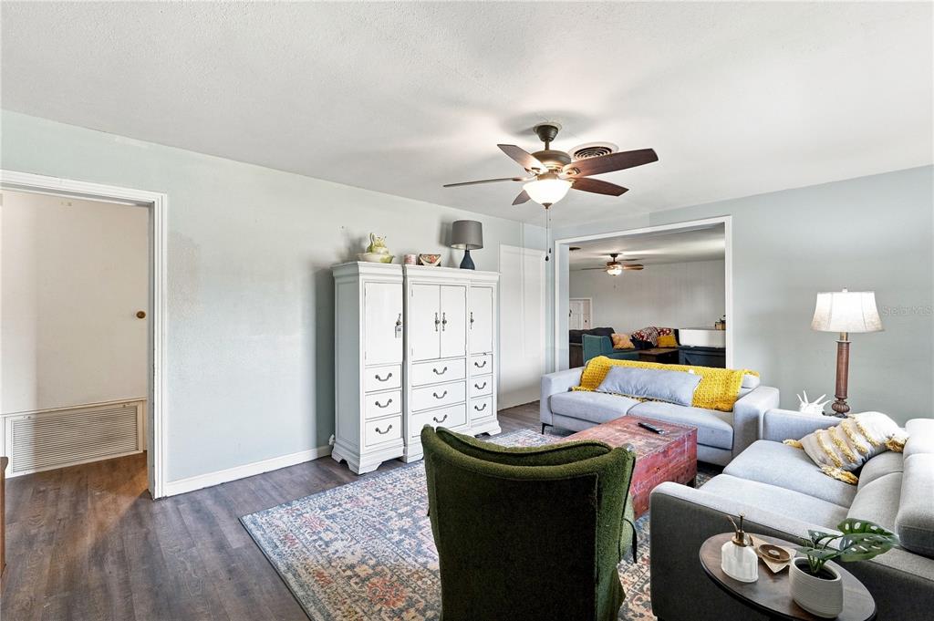 A living room features light blue walls, wood-look flooring, a ceiling fan, and two sofas — 603 N CENTRAL AVENUE, OVIEDO, FL