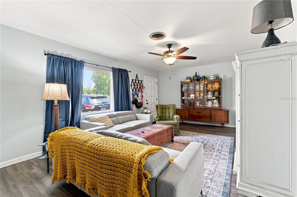 A living room features gray walls, wood-look flooring, a gray sofa, and a wooden hutch — 603 N CENTRAL AVENUE, OVIEDO, FL