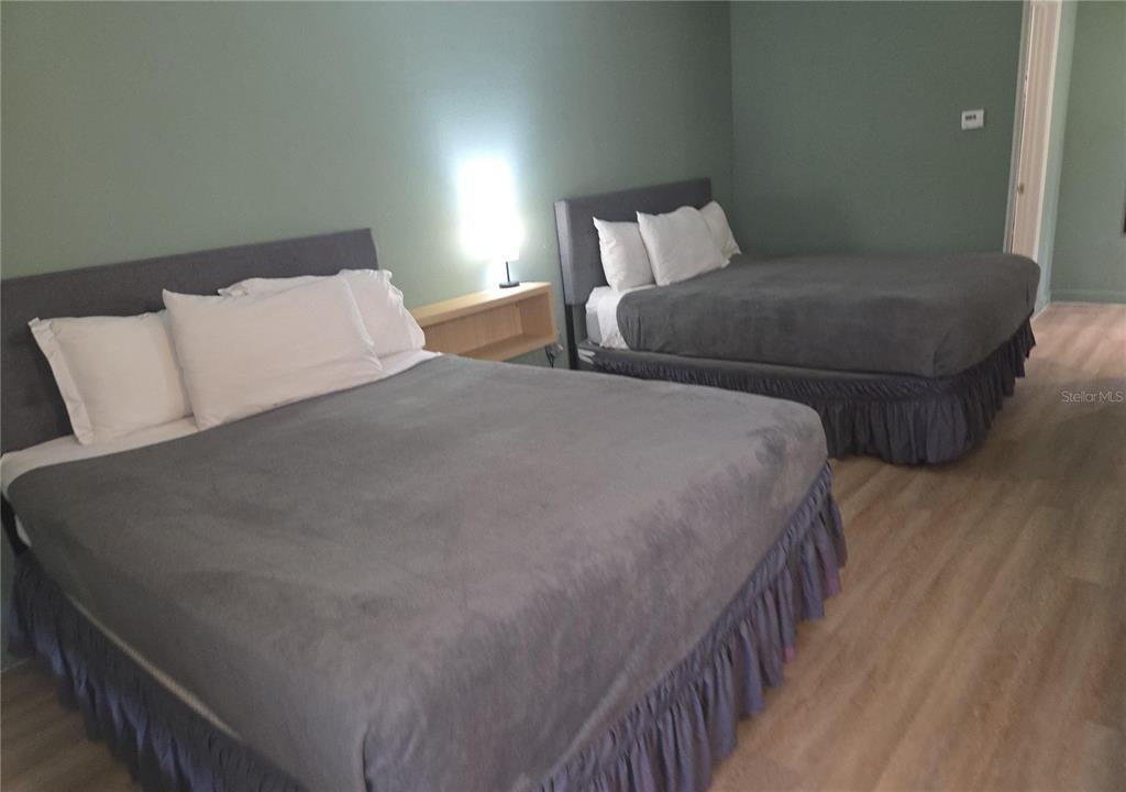 A bedroom features two beds with grey upholstered headboards and matching ruffled bed skirts — 5245 W IRLO BRONSON MEMORIAL HIGHWAY UNIT 258, KISSIMMEE, FL