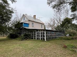 A two-story house with a large, white-latticed porch sits on a grassy lot — 5950 NE HIGHWAY 41, WILLISTON, FL