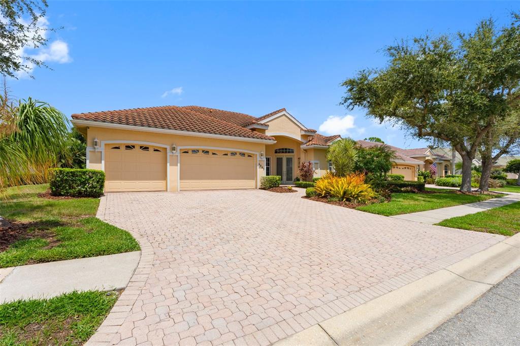 A single-story house with a tan stucco exterior, a tile roof, and a paved driveway — 6803 COYOTE RIDGE COURT, BRADENTON, FL
