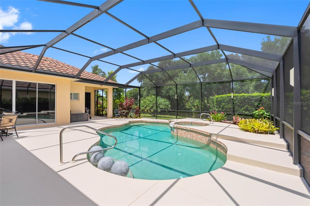 A screened-in patio features a swimming pool with an integrated spa and light-colored decking — 6803 COYOTE RIDGE COURT, BRADENTON, FL