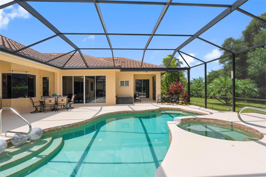 A screened-in patio features a swimming pool, a hot tub, and outdoor dining furniture — 6803 COYOTE RIDGE COURT, BRADENTON, FL