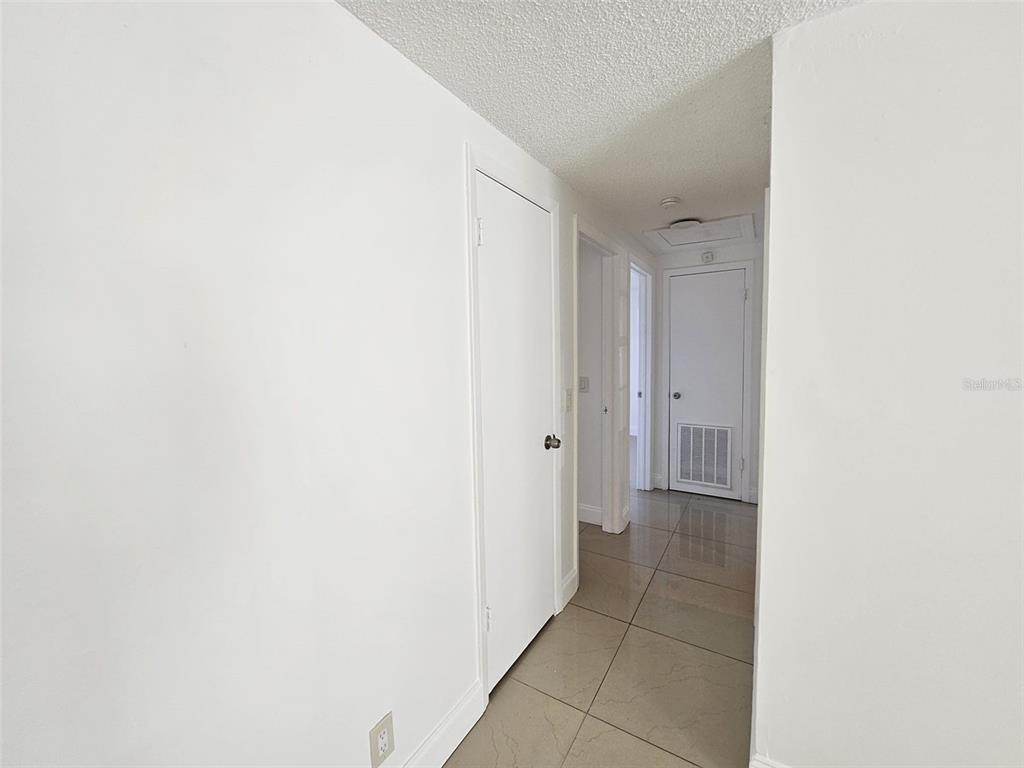 A hallway with white walls, tile flooring, and several closed white doors — 6004 FORTUNE PLACE, APOLLO BEACH, FL