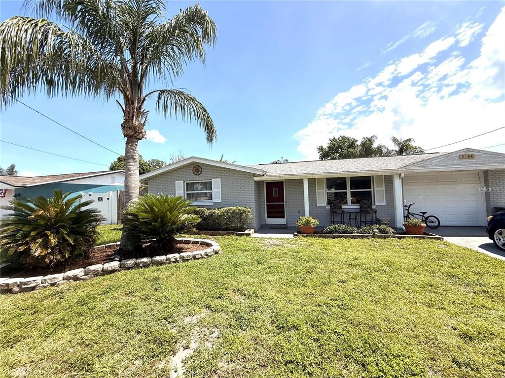 A single-story gray brick house with a palm tree and a front lawn — 5144 CHIME WAY, HOLIDAY, FL