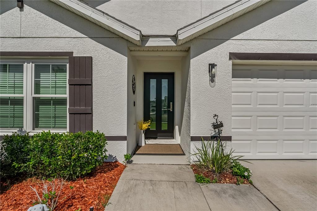 The exterior of a house features a front door, a garage, and a small garden — 8669 TRIUMPH CIRCLE, WILDWOOD, FL