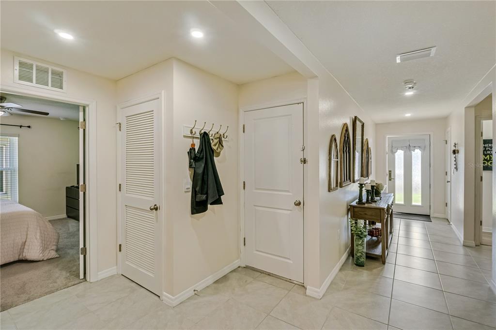 A tiled hallway features a coat rack, two white doors, and a wooden console table — 8669 TRIUMPH CIRCLE, WILDWOOD, FL