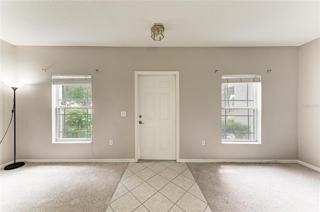 An entryway with a white front door, two windows, beige carpet, and tiled flooring — 14745 AMBERJACK TERRACE UNIT 1, BRADENTON, FL