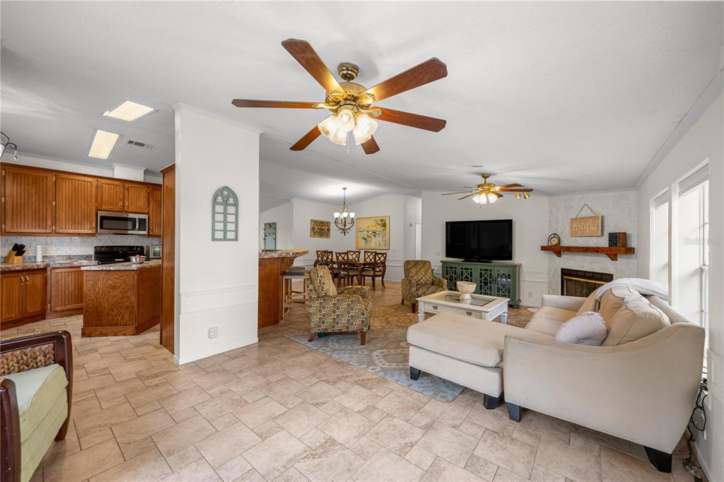 An open-concept living room and kitchen feature tile flooring, wooden cabinets, and a ceiling fan — 18850 SE 12TH LANE, WILLISTON, FL