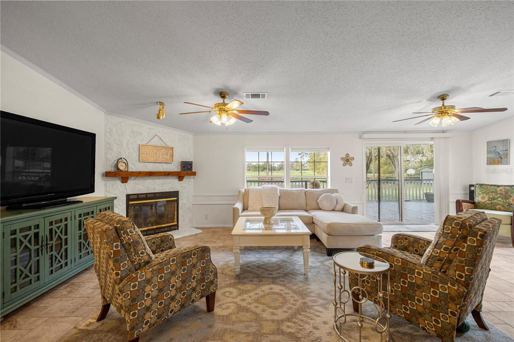 A living room features a fireplace, a sectional sofa, two patterned armchairs, and tile flooring — 18850 SE 12TH LANE, WILLISTON, FL
