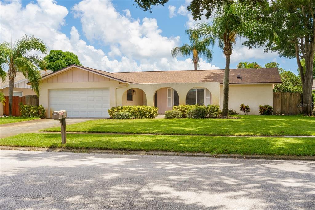 A single-story house with a white garage, arched entryway, and a brown shingled roof — 2419 TIMBERCREST CIRCLE W, CLEARWATER, FL