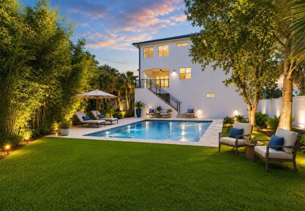 A backyard features a rectangular swimming pool, a lawn, and a multi-story white house — 1956 CEDAR DRIVE, DUNEDIN, FL