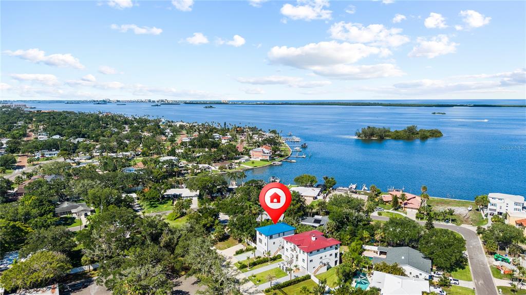 An aerial view shows two multi-story houses near a large body of water — 1956 CEDAR DRIVE, DUNEDIN, FL