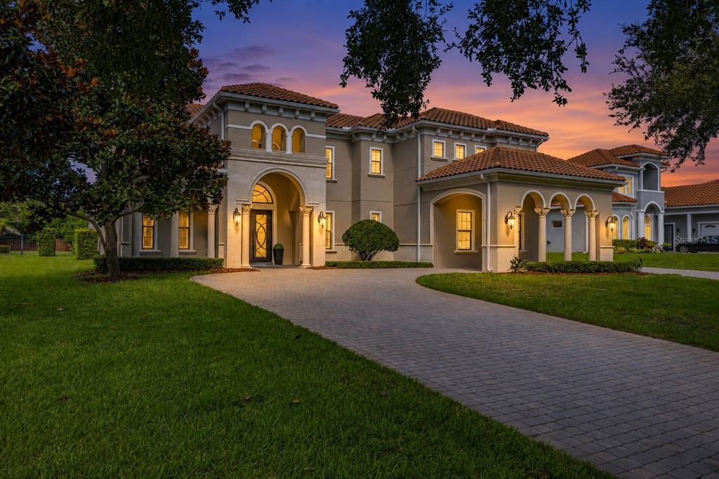 A two-story Mediterranean-style house with a tiled roof, arched entryway, and a paved driveway — 5526 MARLEON DRIVE, WINDERMERE, FL