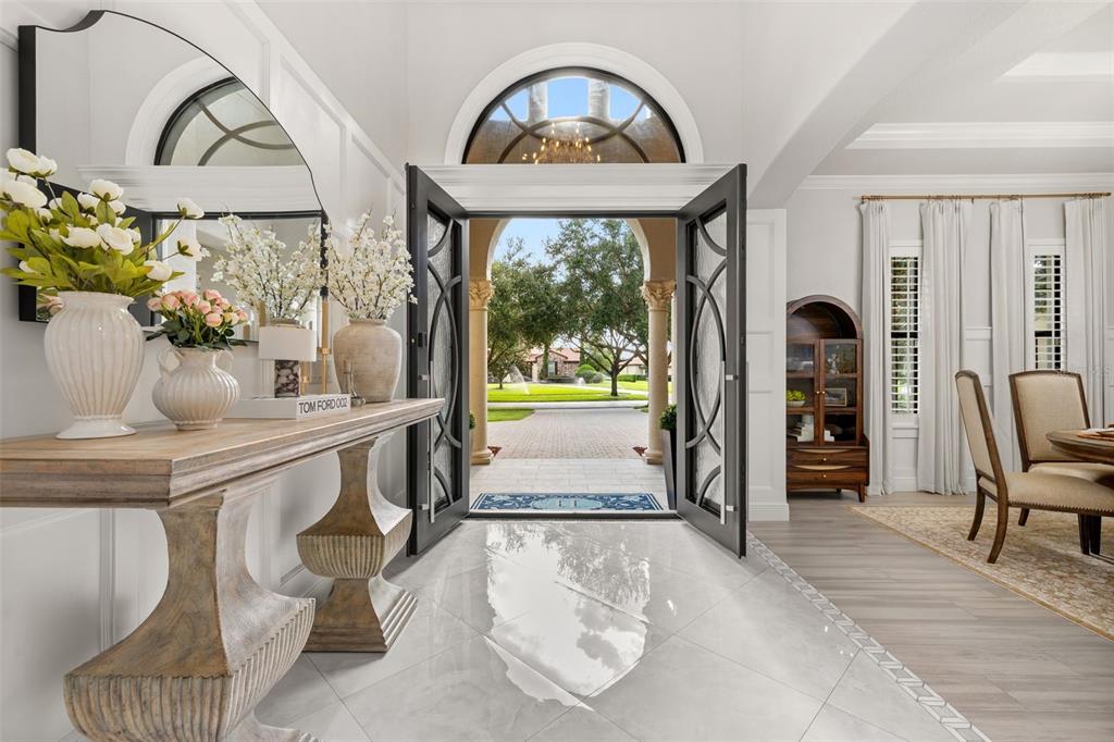 A bright entryway features a wooden console table, marble floors, and double doors opening outside — 5526 MARLEON DRIVE, WINDERMERE, FL