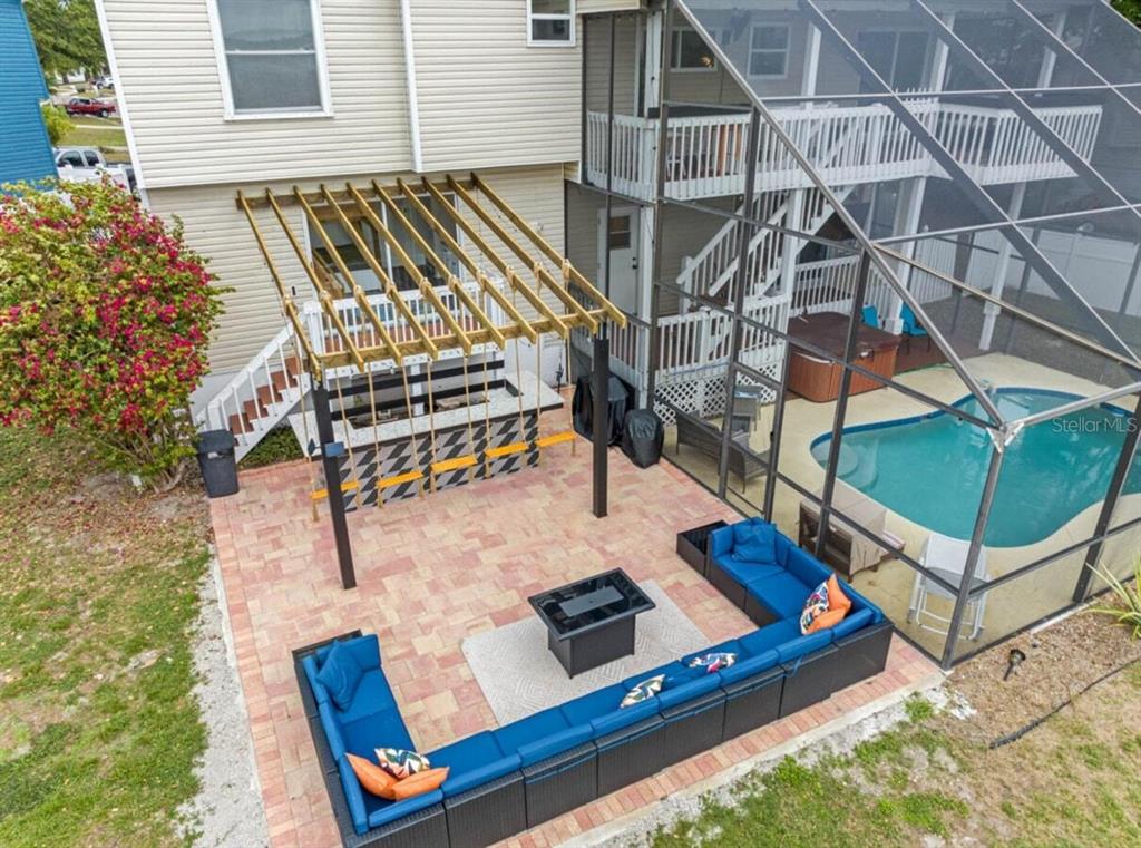 An aerial view of a backyard patio featuring a pergola, outdoor bar, and sectional seating — 12692 PINEWAY DRIVE, LARGO, FL