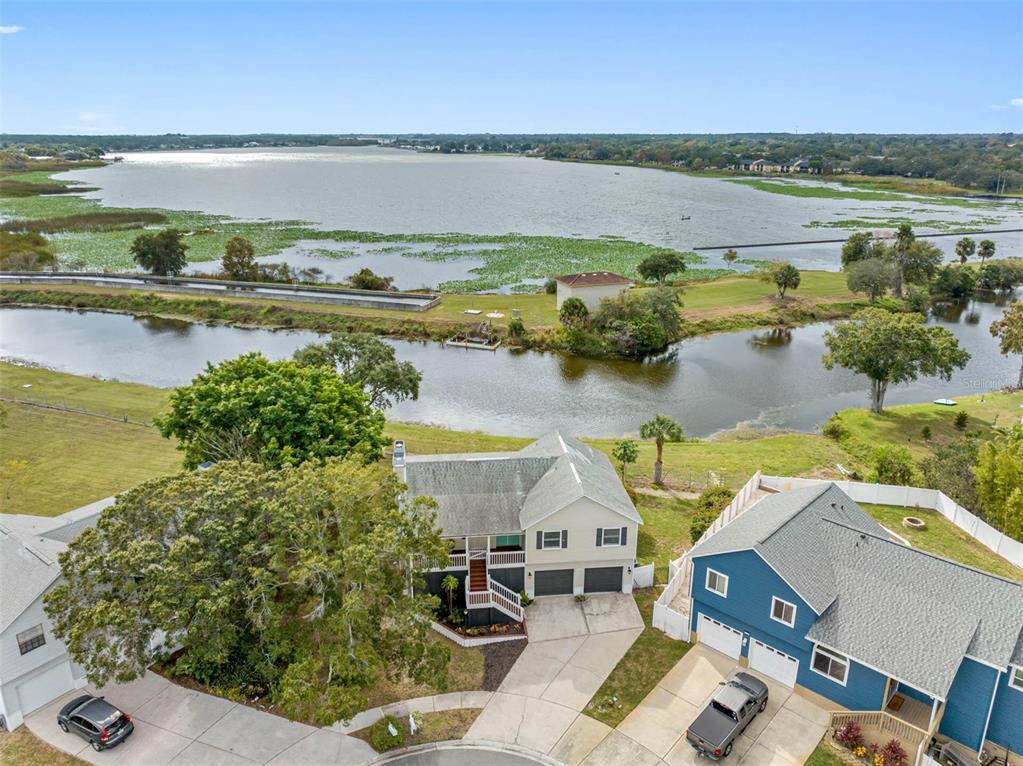 An aerial view shows two houses near a lake with a small canal — 12692 PINEWAY DRIVE, LARGO, FL