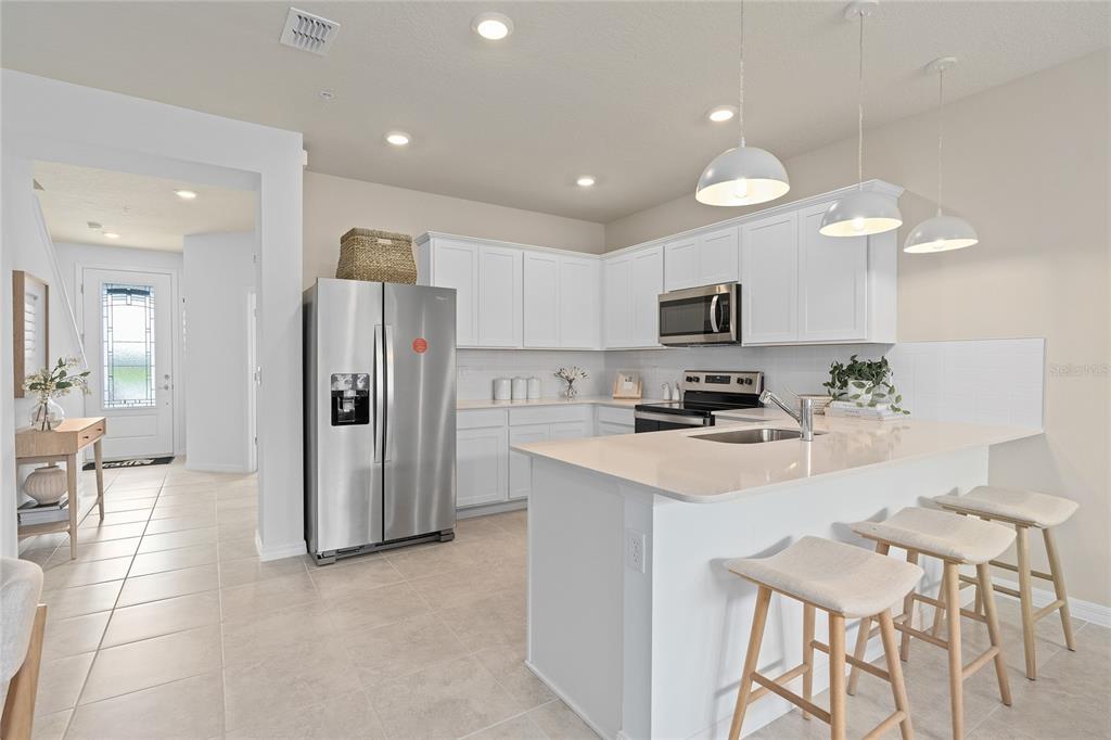A kitchen with white cabinets, stainless steel appliances, a center island, and bar seating — 10502 EVENING STAR STREET STREET, ORLANDO, FL