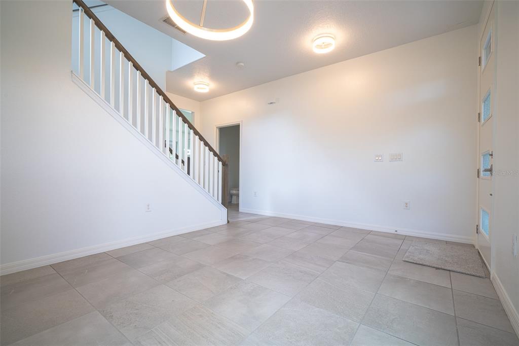 An entryway features light tile flooring, a staircase with white railings, and a front door — 2510 AMATI DRIVE, KISSIMMEE, FL