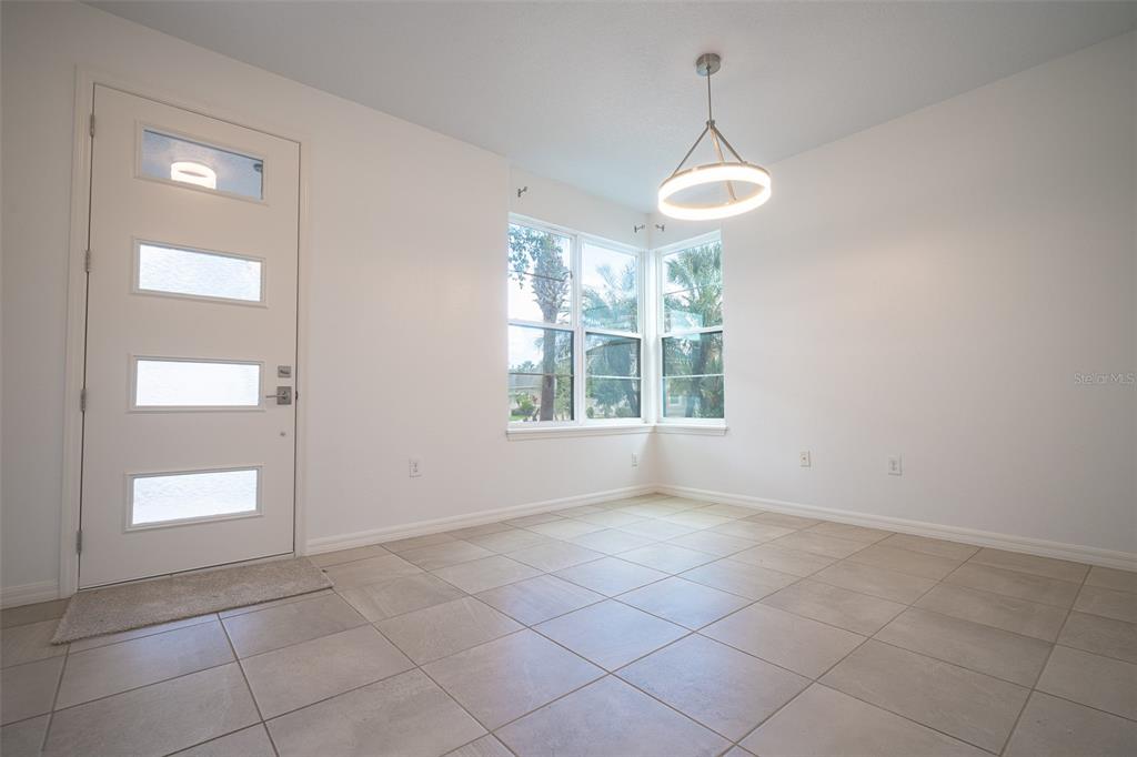 A bright dining area features white walls, tile flooring, a modern pendant light, and corner windows — 2510 AMATI DRIVE, KISSIMMEE, FL
