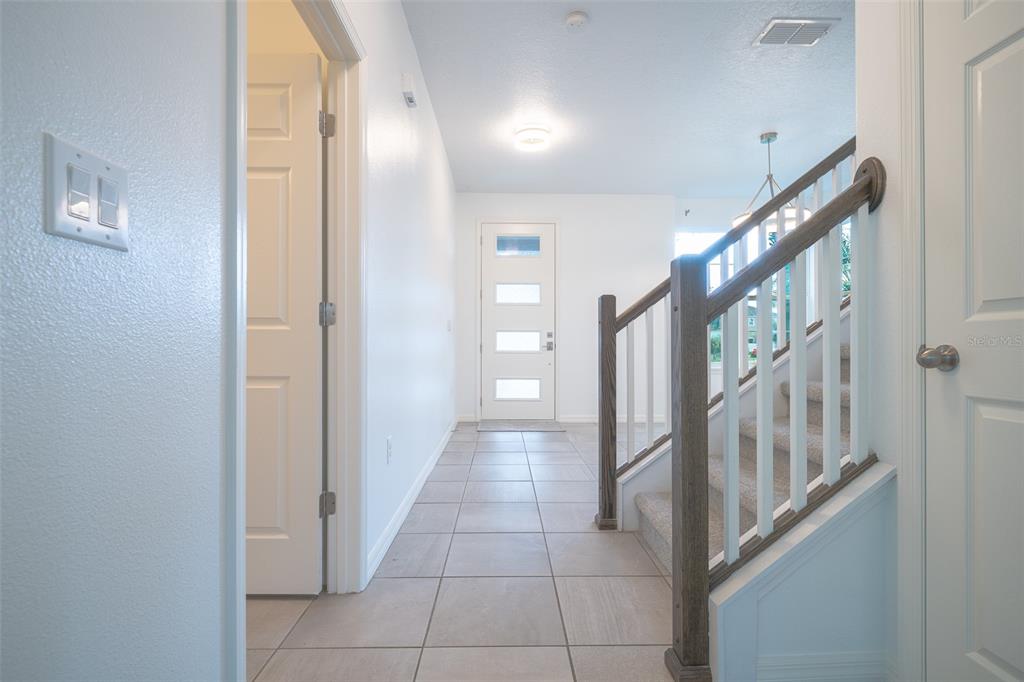 An entryway with tile flooring, a white front door, and a staircase with carpeted steps — 2510 AMATI DRIVE, KISSIMMEE, FL