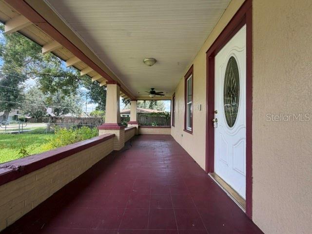 A covered front porch with a red tile floor, brick half-wall, and white front door — 3510 N FLORIDA AVENUE, LAKELAND, FL