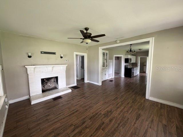 A living room with a white brick fireplace, wood-look flooring, and an open kitchen view — 3510 N FLORIDA AVENUE, LAKELAND, FL