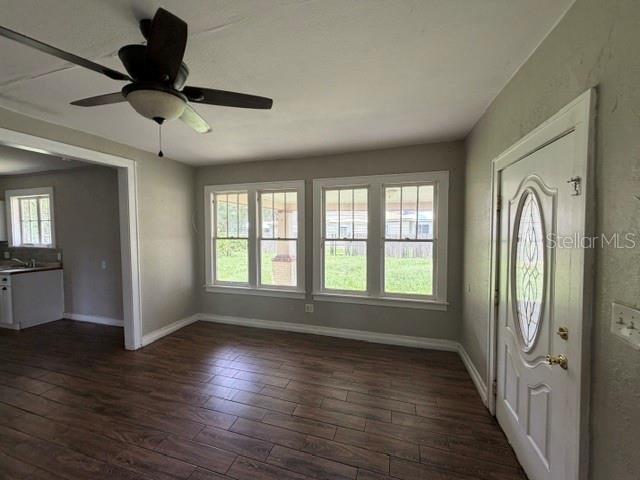 A living room with wood-look tile flooring, a ceiling fan, and a white front door — 3510 N FLORIDA AVENUE, LAKELAND, FL